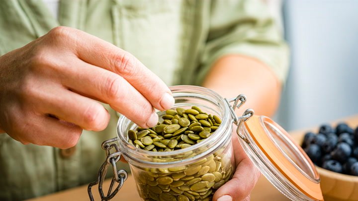 benefits of pumpkin seeds: Someone enjoying a handful of pumpkin seeds as a healthy snack.